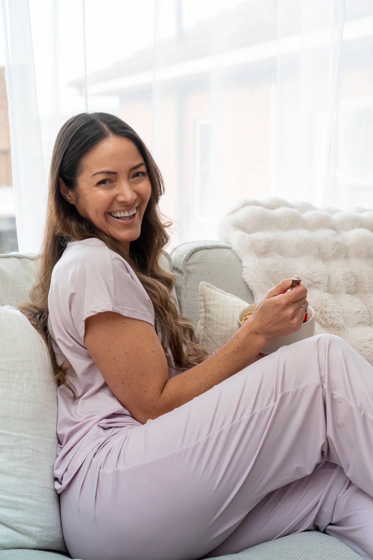 Smiling woman relaxing on a lounge in soft sage lyocell pyjama shorts and tee
